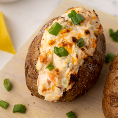 A loaded Air Fryer Seafood Baked Potato topped with creamy seafood filling, garnished with fresh herbs, served on a white plate.