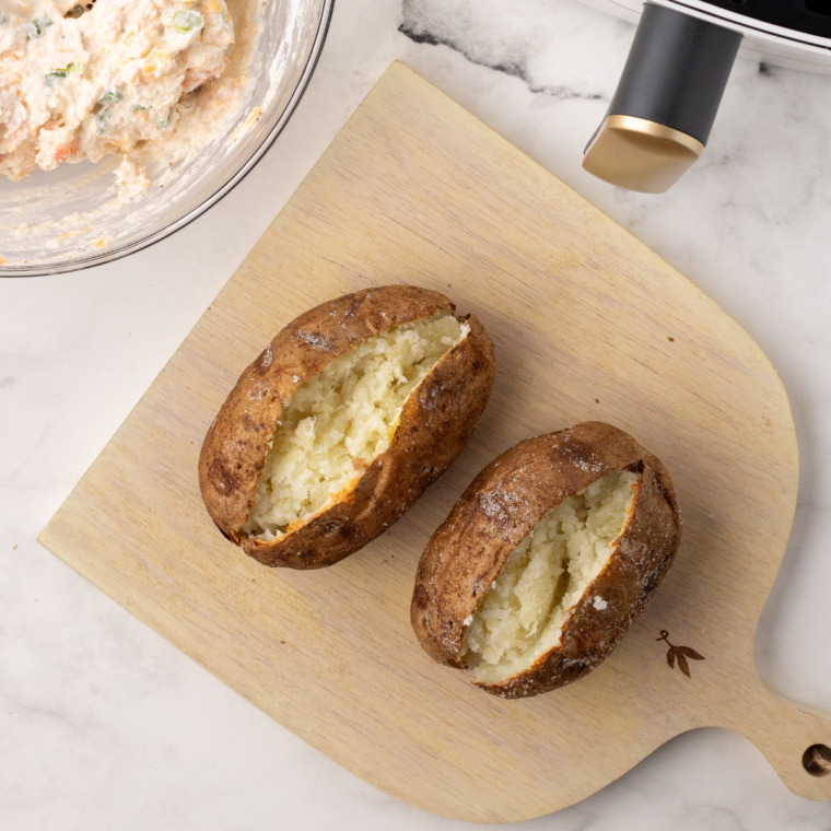 "Carefully slice open the cooked potatoes, fluff the insides with a fork, and stuff them generously with the prepared seafood mixture."
