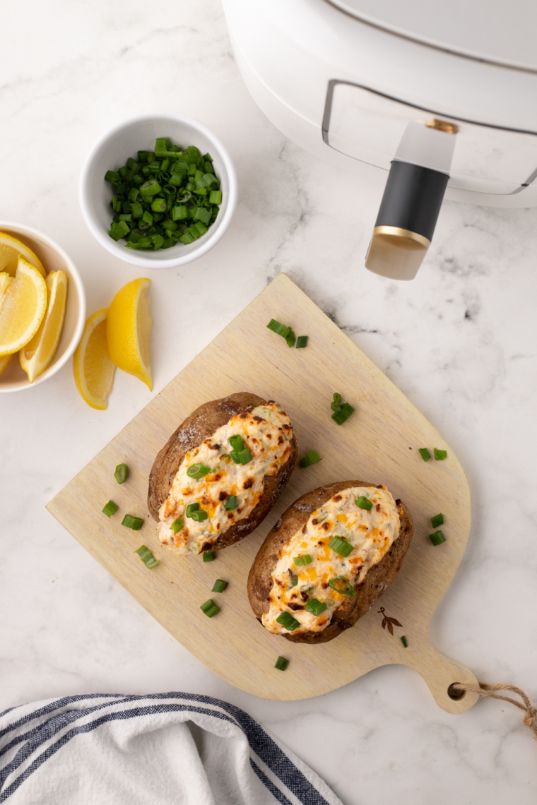 Air Fryer Seafood Baked Potato with shrimp, crab, and creamy cheese topping, served hot and garnished with green onions.