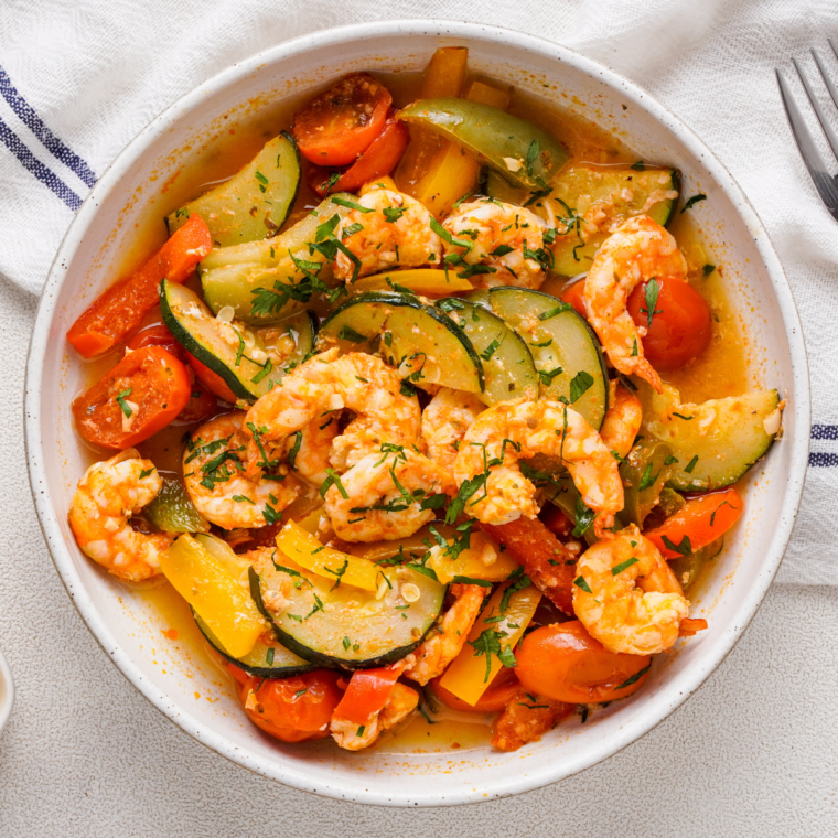 Air fryer shrimp foil packets with shrimp, cherry tomatoes, zucchini, and bell peppers in a foil wrap.