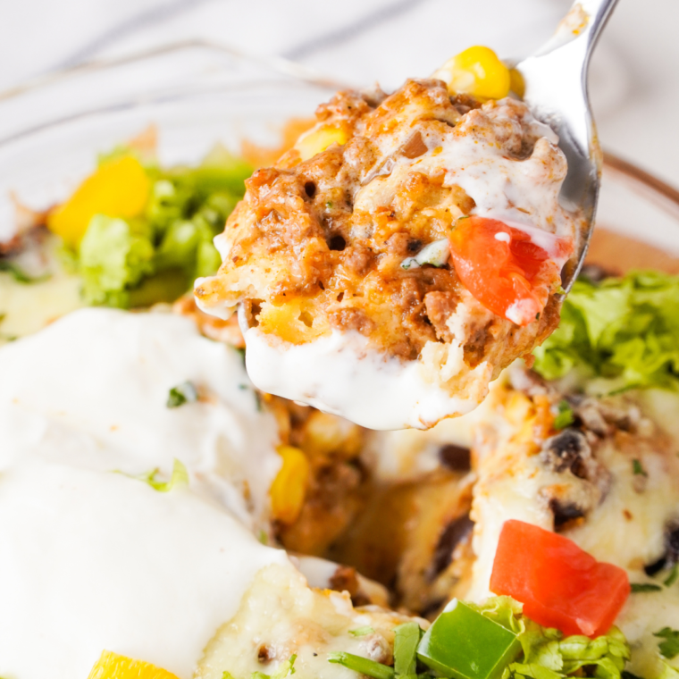 "Serving of Air Fryer Taco Fiesta Bubble Up Casserole in a bowl, garnished with sour cream and jalapeño slices."