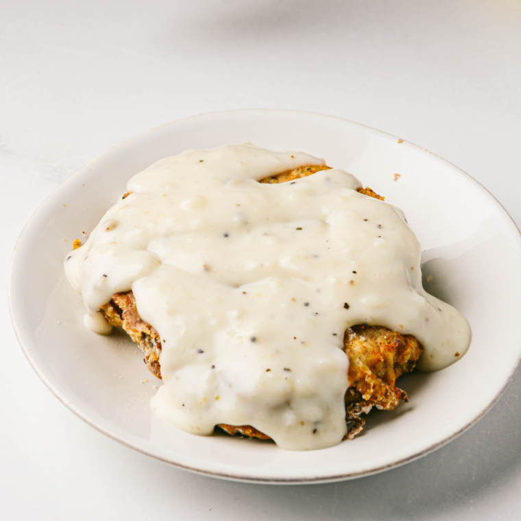 Plate of golden, crispy air fryer Texas Roadhouse Country Fried Chicken served with creamy gravy and mashed potatoes.