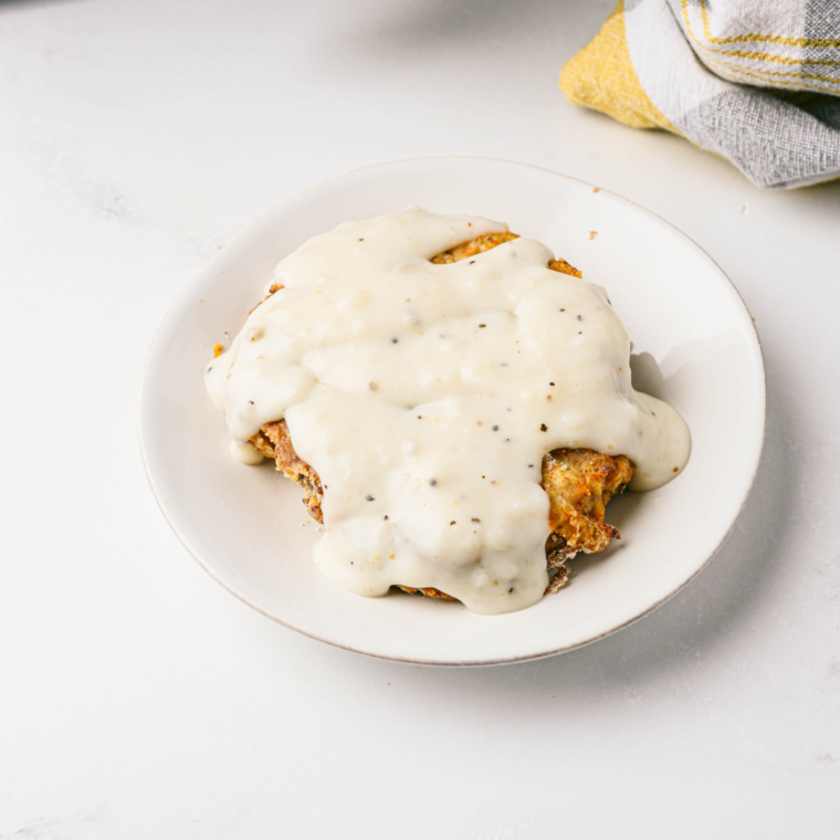 Plate of golden, crispy air fryer Texas Roadhouse Country Fried Chicken served with creamy gravy and mashed potatoes.