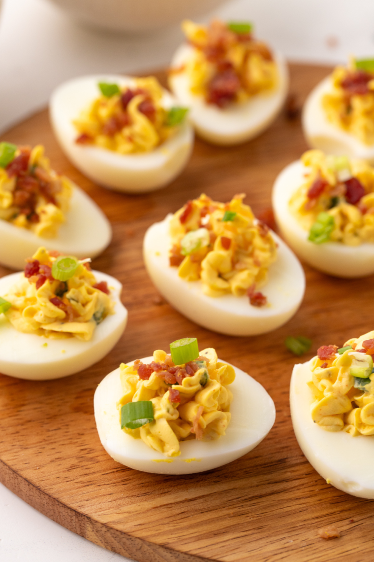 "Black Garlic Deviled Eggs with creamy filling topped with paprika and fresh herbs."