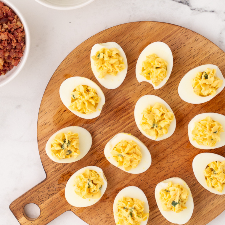 Black Garlic Deviled Eggs on a plate, garnished with herbs."