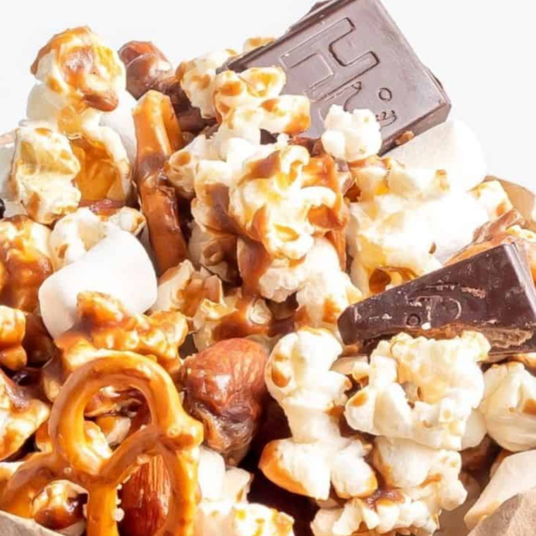 "Air Fryer Moose Munch Caramel Popcorn in a bowl, featuring golden caramel-coated popcorn mixed with nuts and drizzled with chocolate."