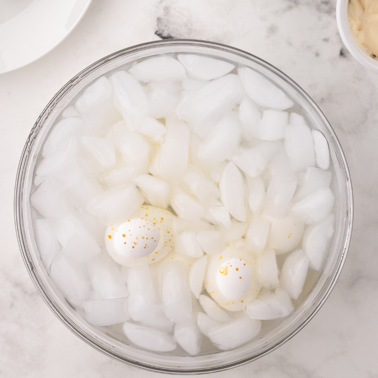 "Transfer cooked eggs to a bowl of ice water to cool for 5-10 minutes before peeling."