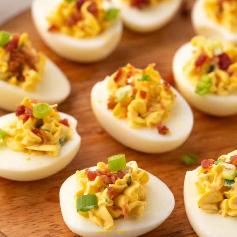 Black Garlic Deviled Eggs garnished with fresh herbs and a sprinkle of paprika, served on a plate.