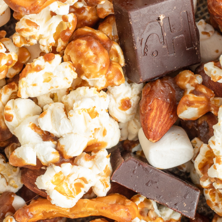 A bowl of homemade Moose Munch Caramel Popcorn, featuring caramel-coated popcorn, nuts, and drizzled chocolate, served as a festive snack.