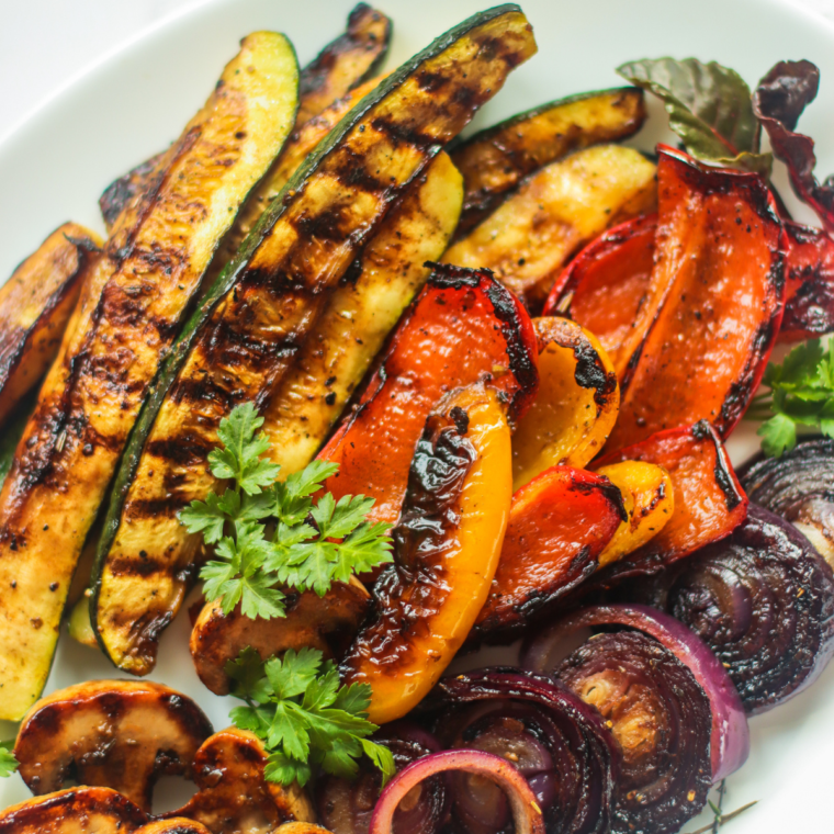 Colorful balsamic vegetables cooking on a Blackstone griddle, including zucchini, bell peppers, onions, and mushrooms.