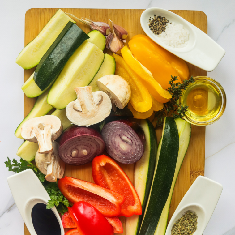 Diced vegetables, and seasonings on cutting board, with olive oil.