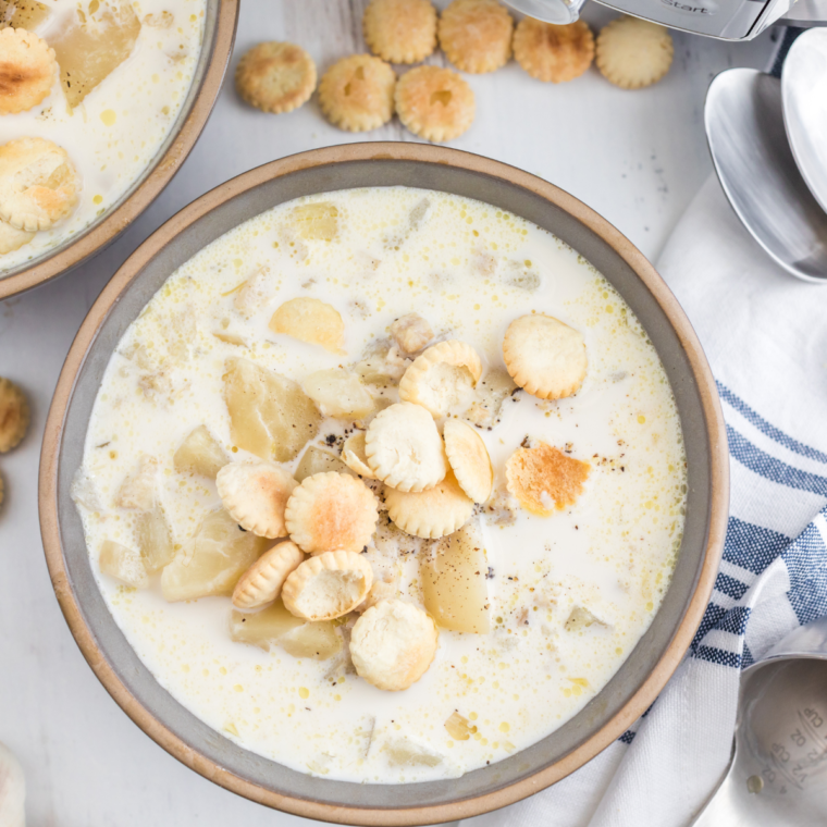 A bowl of creamy Red Lobster-style clam chowder, topped with fresh herbs and served with crusty bread for dipping.