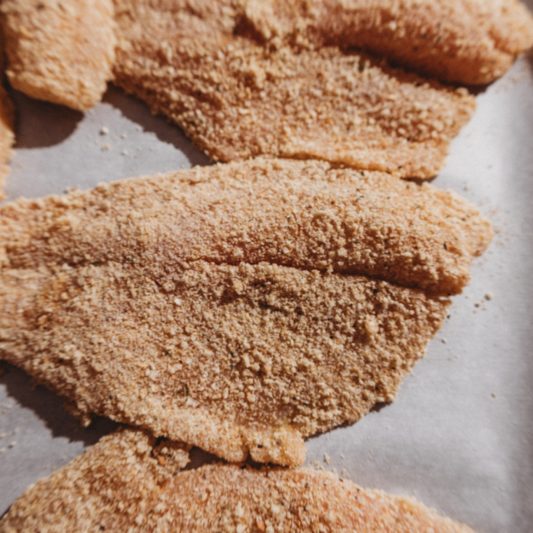 Battered fish place on parchment paper, waiting to be cooked.