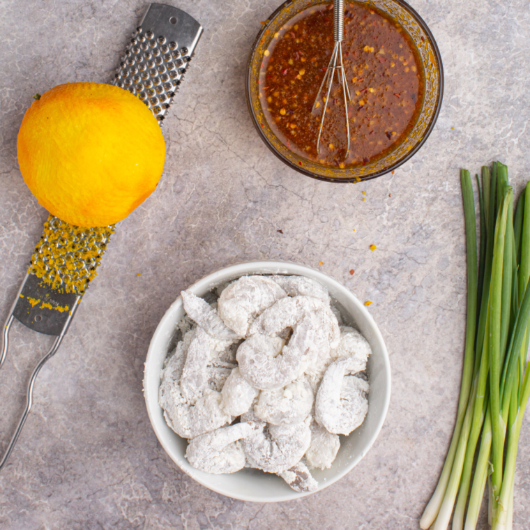 Preparing shrimp by coating with flour, cornstarch, and egg mixture for crispy texture in Copycat P.F. Chang’s Dynamite Shrimp recipe.