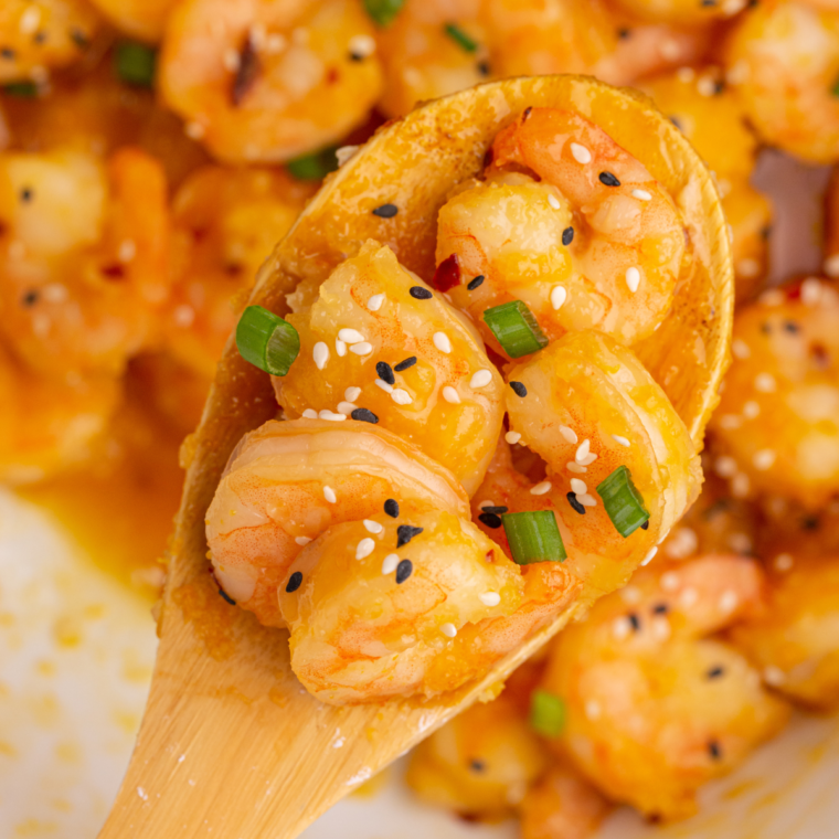 "Copycat P.F. Chang’s Dynamite Shrimp served crispy and coated in a spicy, creamy sauce, garnished with sesame seeds and green onions."