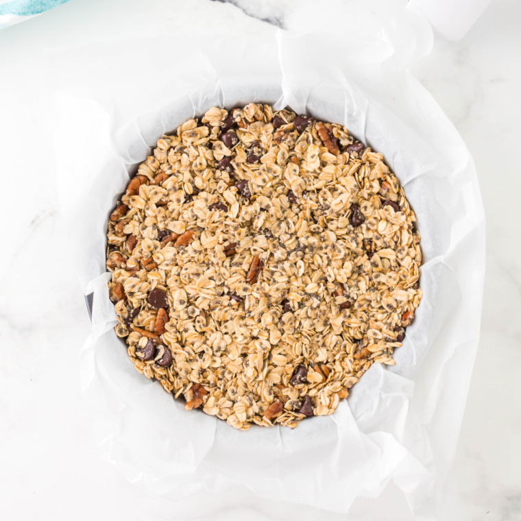 Granola mixture spread evenly in air fryer basket before cooking.