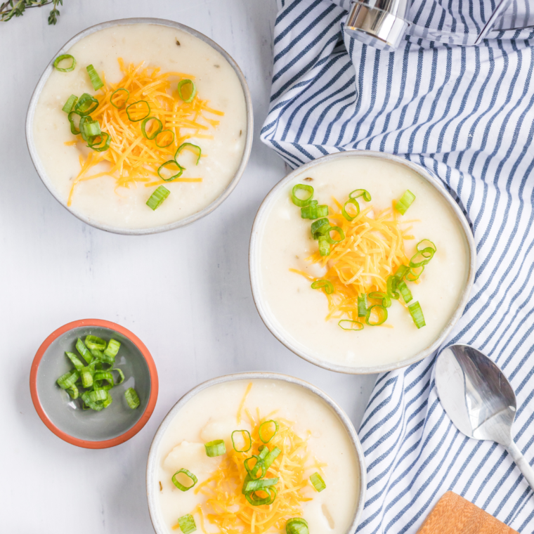 Bowl of creamy Eat N Park Potato Soup topped with shredded cheddar cheese and chives, served hot.