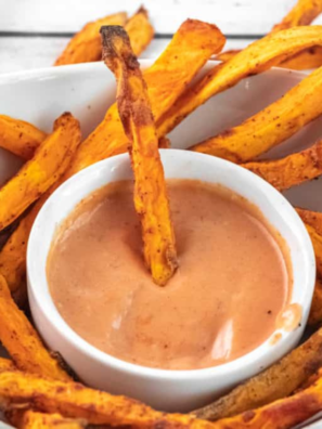 "A small bowl of spicy Flamethrower Sauce surrounded by dipping fries, showcasing its creamy and bold texture."