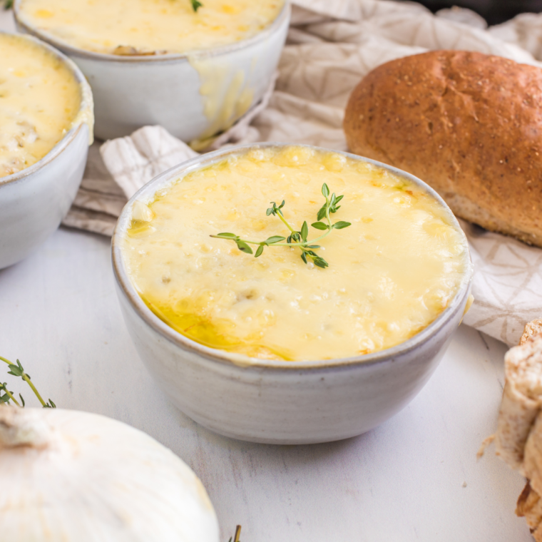 Bowl of Longhorn French Onion Soup topped with melted cheese and a toasted baguette slice.