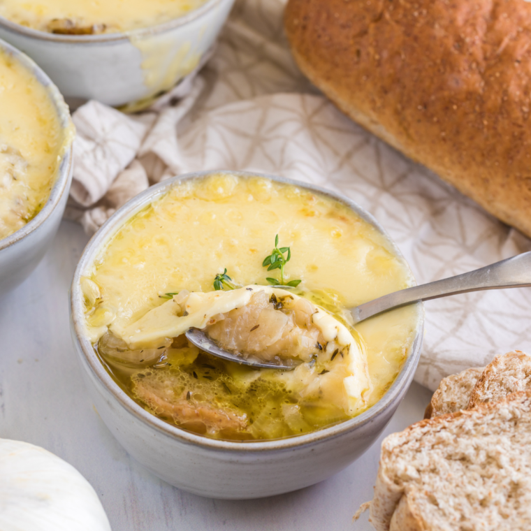 Bowl of Longhorn French Onion Soup topped with melted cheese and toasted baguette slice, served in a rustic bowl.