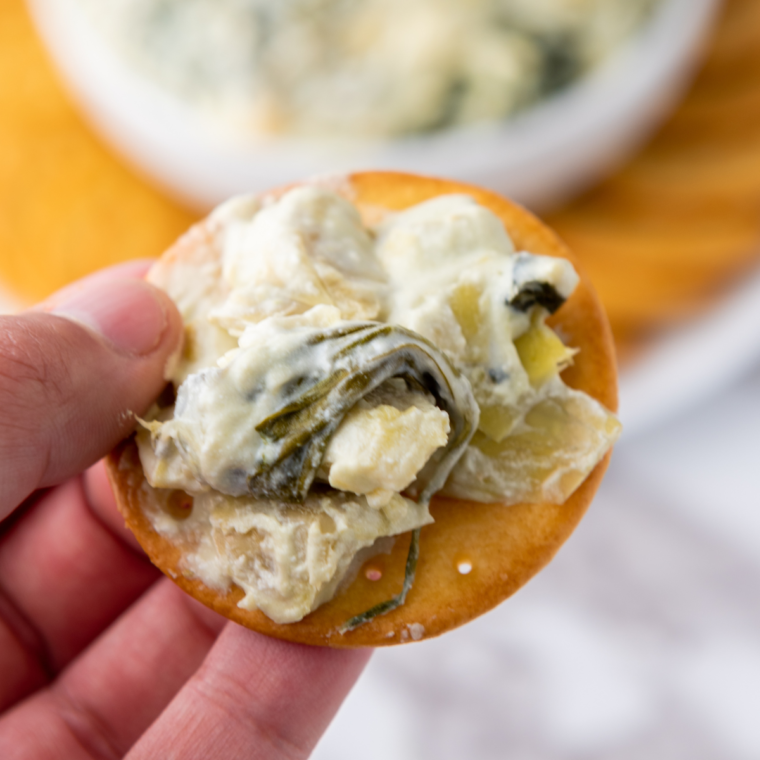Close-up of creamy spinach artichoke dip cooked in Ninja Foodi Possible Cooker Pro, topped with melted cheese.