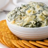 "Delicious and creamy Ninja Foodi Possible Cooker Pro Spinach Artichoke Dip with melted cheese and fresh vegetables."