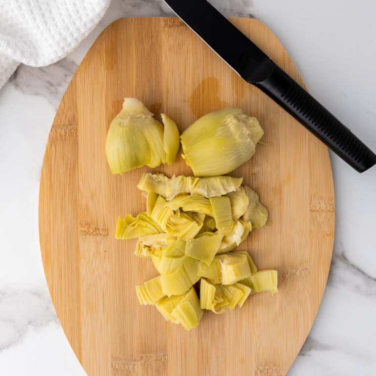 Cut artichoke hearts on kitchen table.