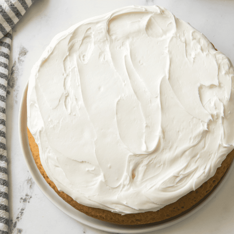 Butter cake batter smoothed evenly into a parchment-lined round pan before baking