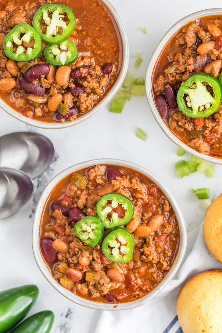 A bowl of homemade Panera Turkey Chili copycat recipe, filled with ground turkey, beans, and vegetables, garnished with fresh cilantro and served with a side of crusty bread.