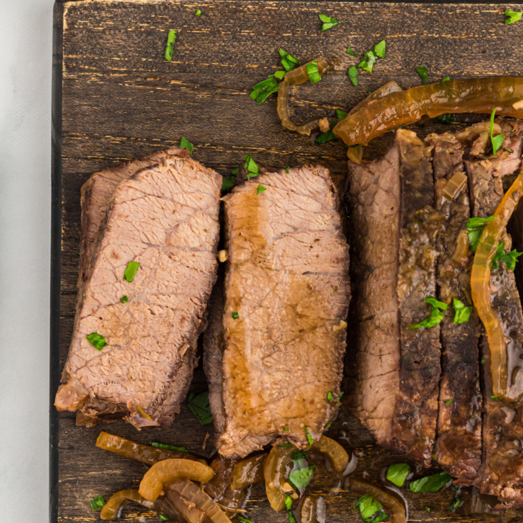 Close up view of sliced flank steak with onions and sauce