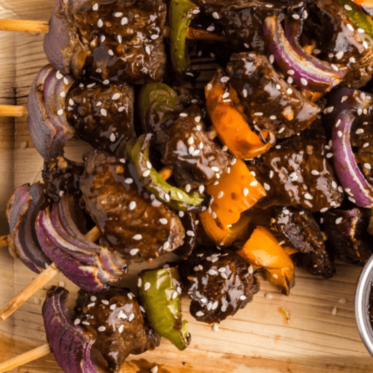 A plate of steak kabobs with sirloin, bell peppers, and mushrooms served on a platter, perfect for a tasty Texas Roadhouse-inspired meal."