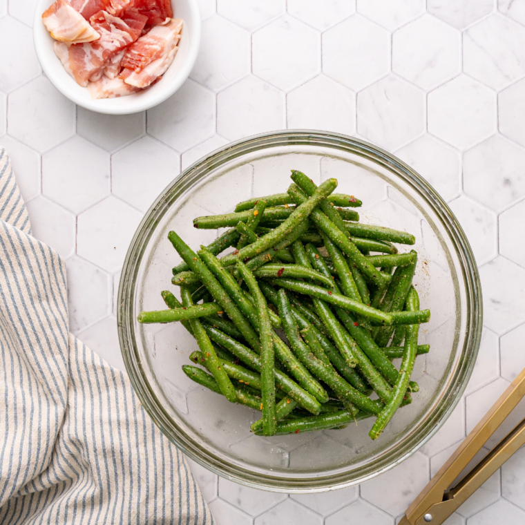 Fresh green beans being trimmed on a cutting board, ready to be blanched.