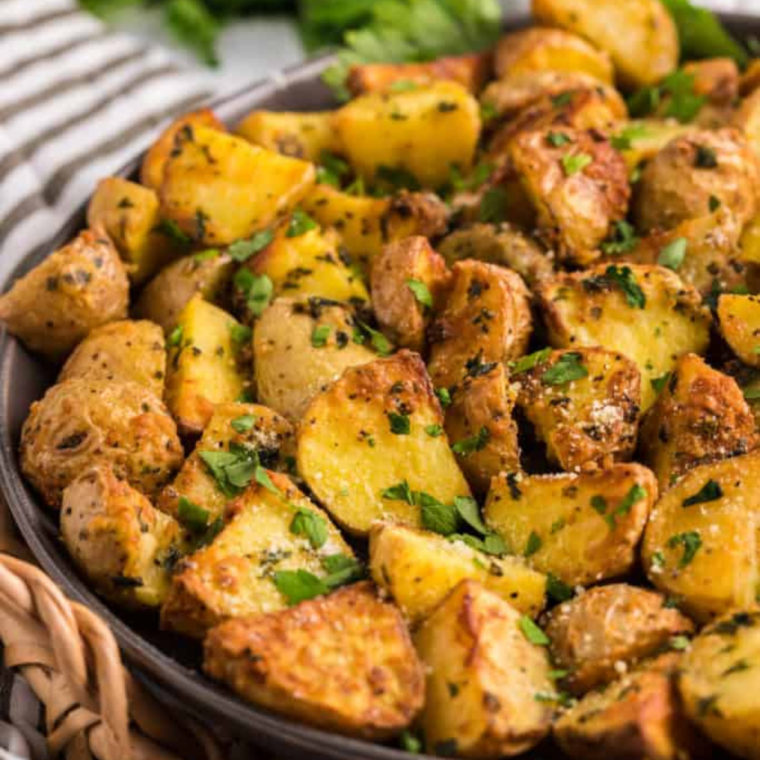 Close-up of golden, crispy Vesuvio Potatoes garnished with garlic and herbs."