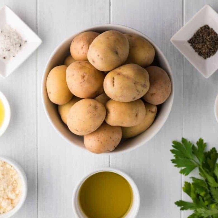 Ingredients for Vesuvio Potatoes including russet potatoes, garlic, fresh herbs, and white wine.