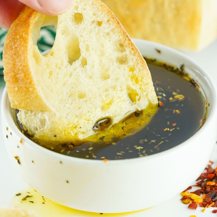 Mediterranean bread dipping oil in a small bowl with olive oil, balsamic vinegar, garlic, herbs, and spices for a flavorful appetizer.