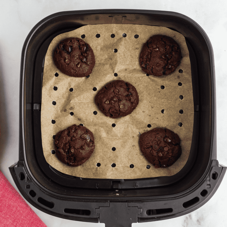 Prepare the air fryer by using a baking tray or lining the basket with parchment paper, ensuring holes are poked in the paper. Arrange cookie dough balls 2 inches apart, baking in batches as necessary.