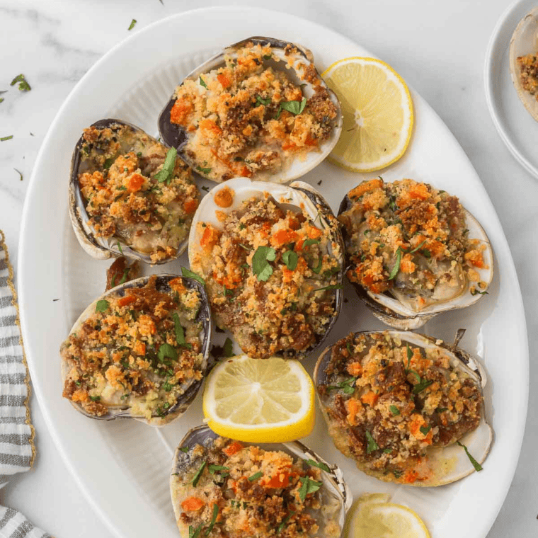Golden and crispy Air Fryer Clam Casino topped with breadcrumbs, bacon, and fresh herbs, served on a white platter with lemon wedges.