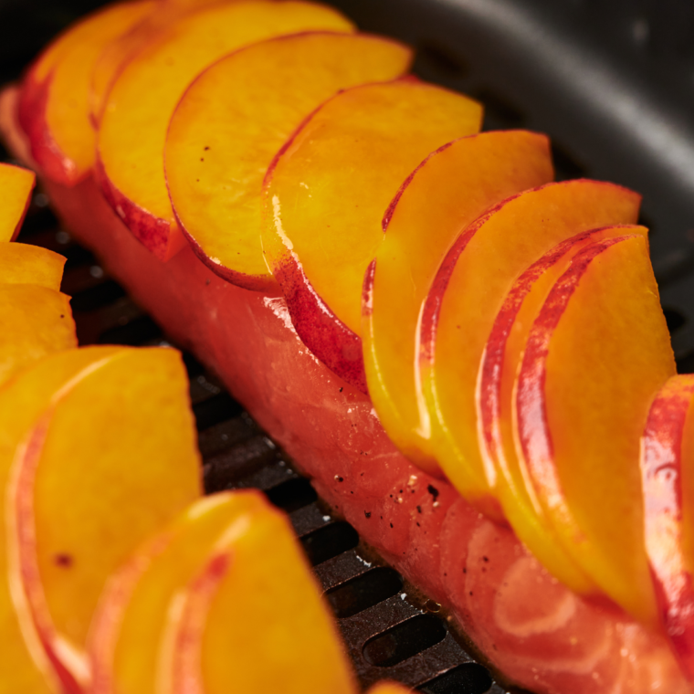 Preheating the air fryer to 400°F and cooking salmon fillets for 8-10 minutes, brushing with peach glaze during the last 2 minutes.