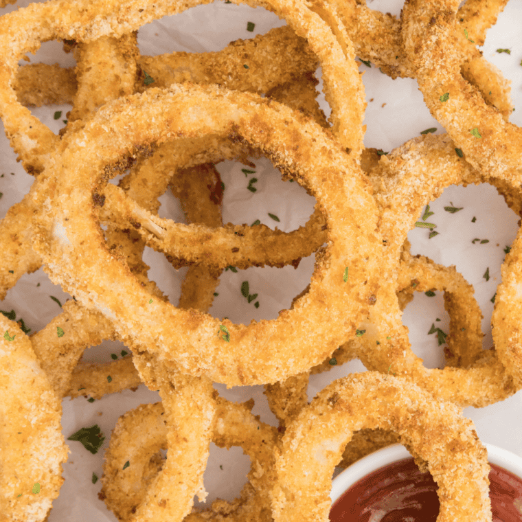 Golden and crispy Applebee’s Onion Rings Copycat Recipe served on a plate with a side of dipping sauce.