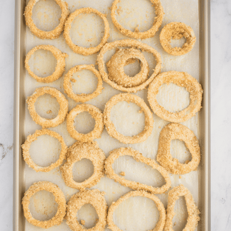 Step-by-step coating process for onion rings: dipping in flour mixture, egg wash, and panko breadcrumbs for a crispy texture.