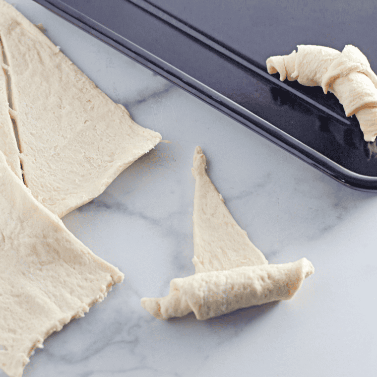 Rolled croissant dough shaped into crescents on a parchment-lined tray, ready for air frying.