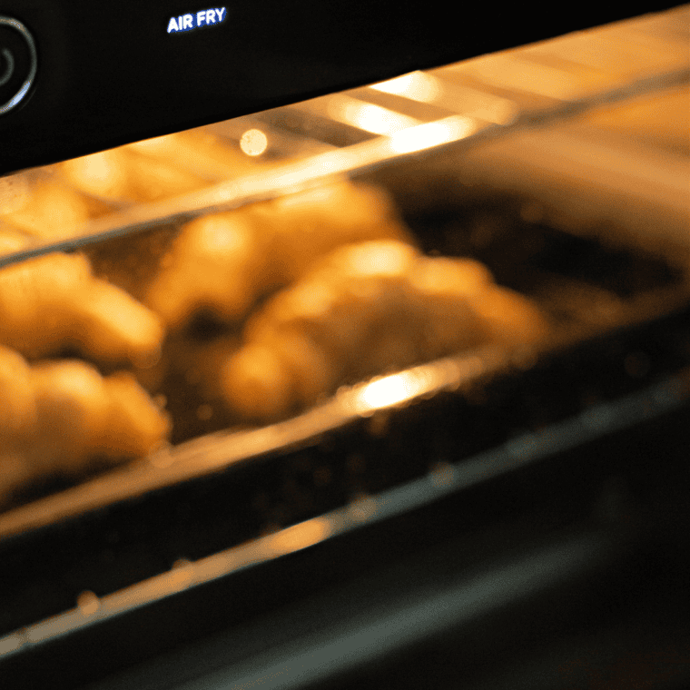 Small saucepan with melted butter, honey, powdered sugar, and vanilla being stirred into a smooth honey butter glaze.