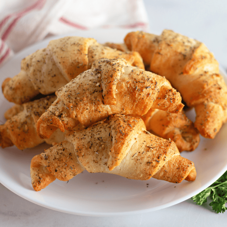 Golden Cheddar's Honey Butter Croissants drizzled with sweet honey butter, served on a white plate.