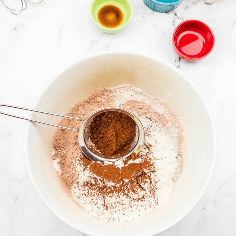 Sifting together all-purpose flour, cocoa powder, baking powder, and sugar in a large mixing bowl for Copycat Portillo’s Chocolate Cake.