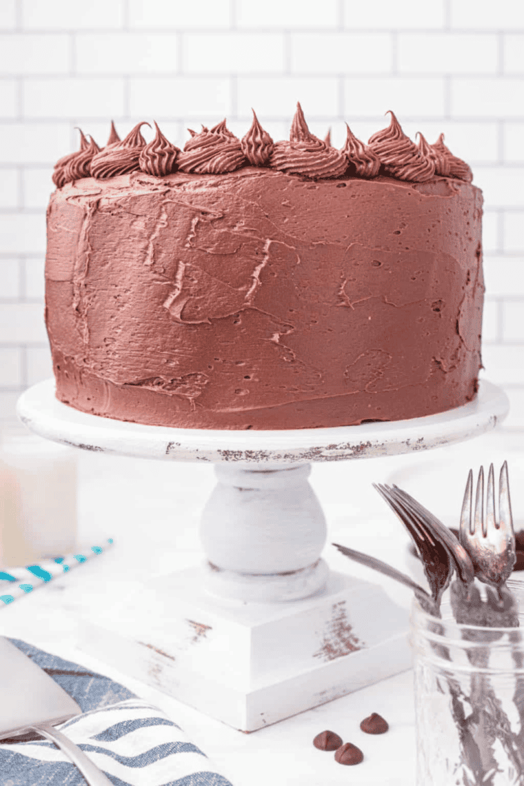 Slice of Copycat Portillo’s Chocolate Cake topped with creamy chocolate frosting, served on a plate.