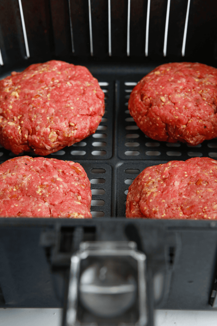 Air fryer basket with burger patties cooking, flipped halfway through, for perfect doneness.