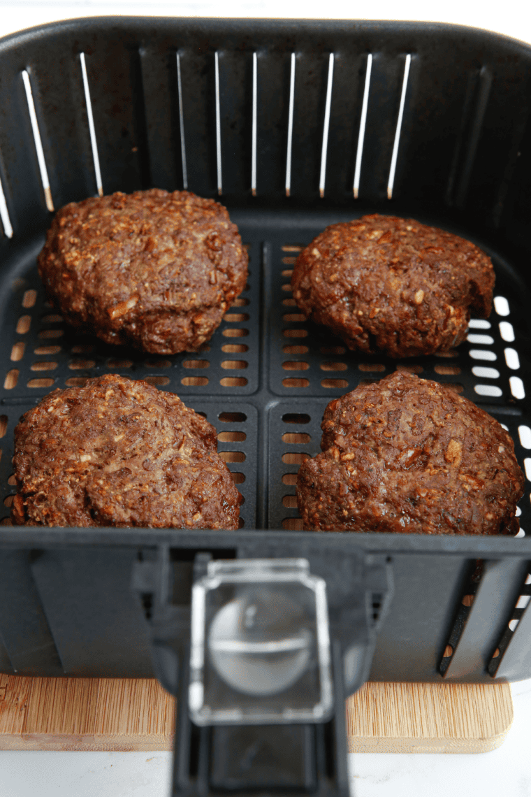 Pretzel buns sliced in half and toasting in the air fryer for a golden, crispy finish.