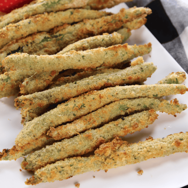 Air fryer crispy green beans in a single layer in the basket, golden brown and crunchy, ready to be served.