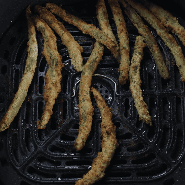 Preheat the air fryer to 375°F, spray basket with oil, arrange coated green beans in a single layer, and air fry for 8-10 minutes until golden and crispy, shaking halfway through.