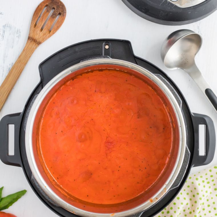 
Pouring vegetable broth into a pot with sautéed onions, garlic, and tomatoes, seasoned with salt and pepper, simmering to blend flavors.